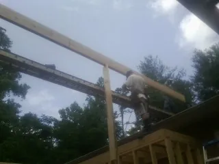 Carpenter setting a ridge beam over a new addition frame — Ice Dam Removal by Roofing Brothers in Montvale