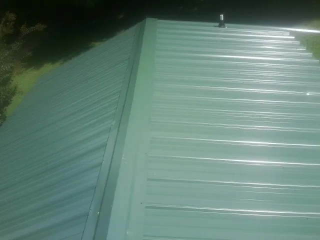 New green metal panels meeting at the ridge of a roof — Flat Roof Repair work by our crew in Montvale
