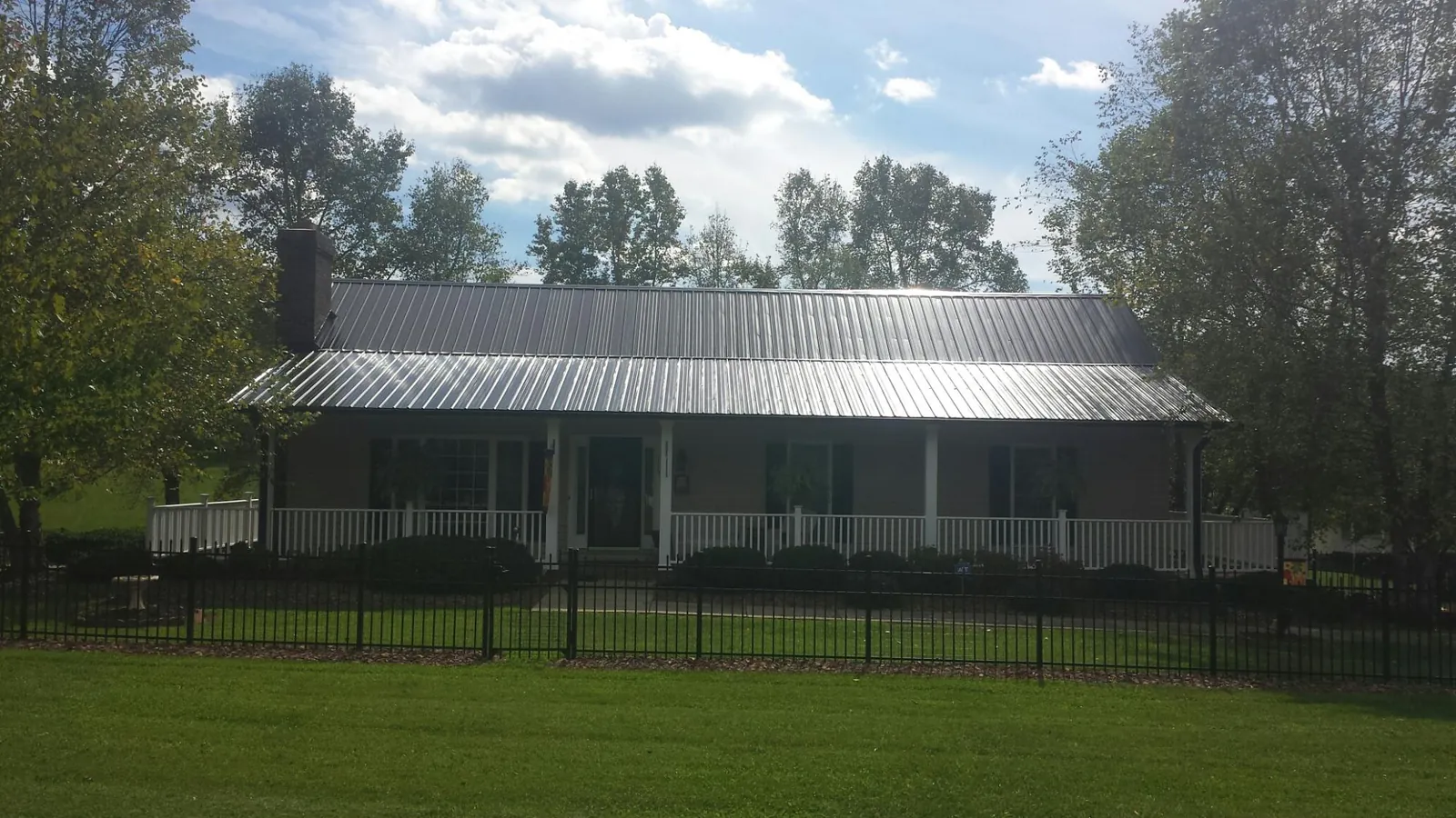 Gray metal roof on a brick ranch with a full width front porch — Gutter Guard Installation work by our crew in Montvale
