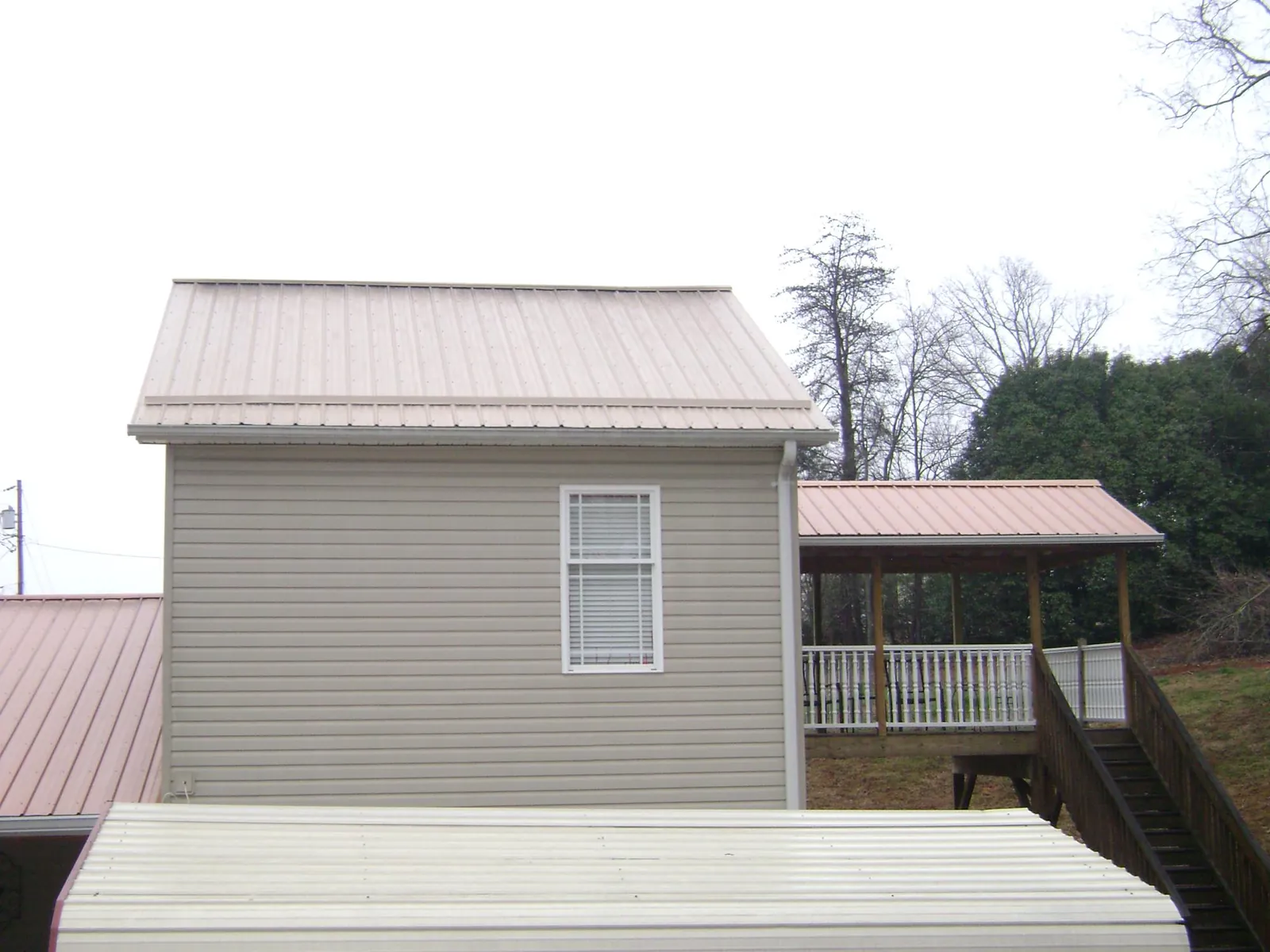 Tan metal roofs on a two story addition and attached porch, from a Roof Replacement job in Montvale