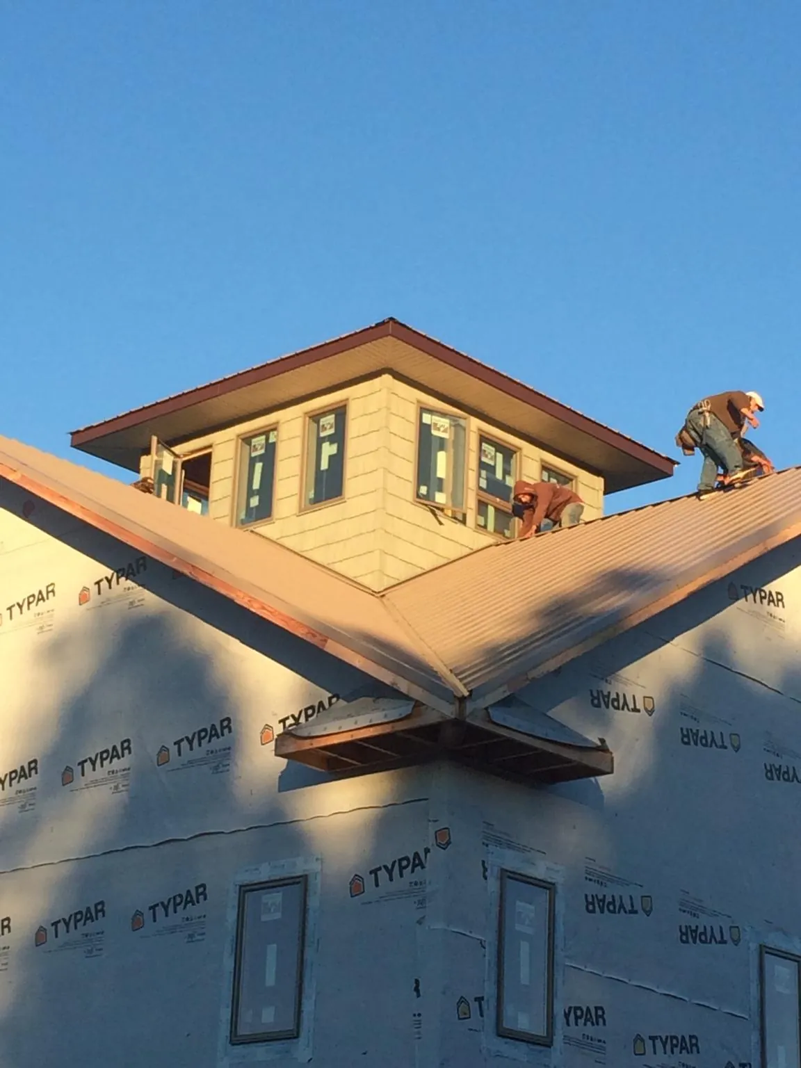 Roofers working around a rooftop cupola on a new metal roof at sunset — Roof Waterproofing in Montvale by Roofing Brothers